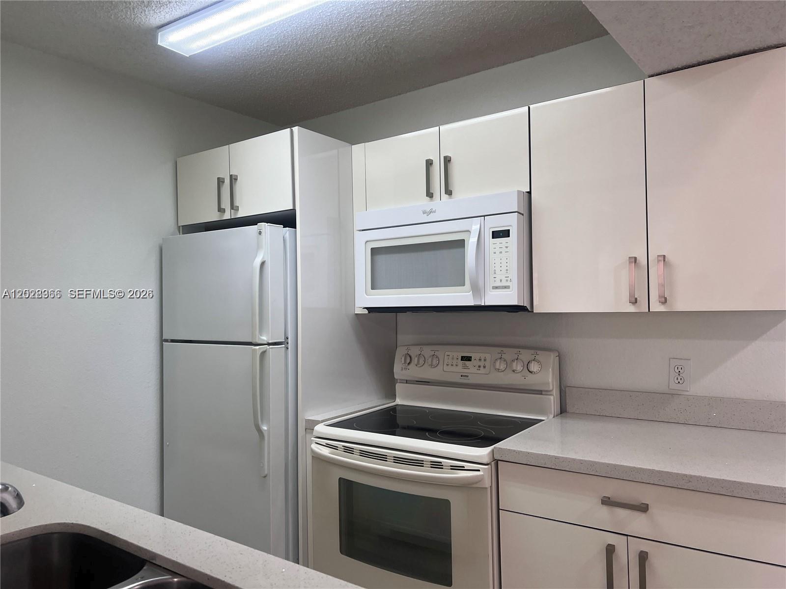 A kitchen features white cabinets, white appliances, and light-colored countertops — 10441 SW 156th Ct # 425, Miami FL 33196, MIAMI, FL