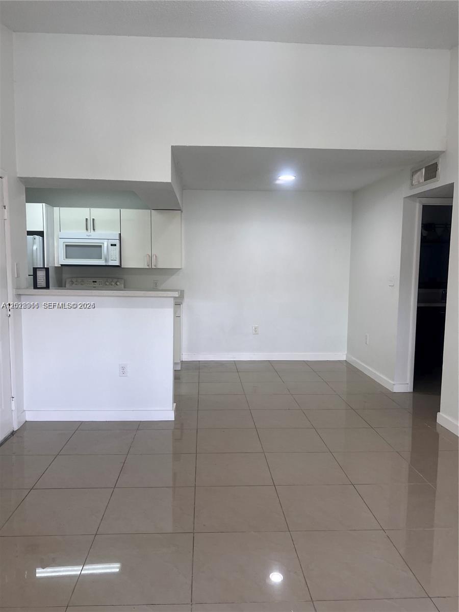 This room features white walls, tile flooring, and a kitchen with white cabinets — 10441 SW 156th Ct # 425, Miami FL 33196, MIAMI, FL
