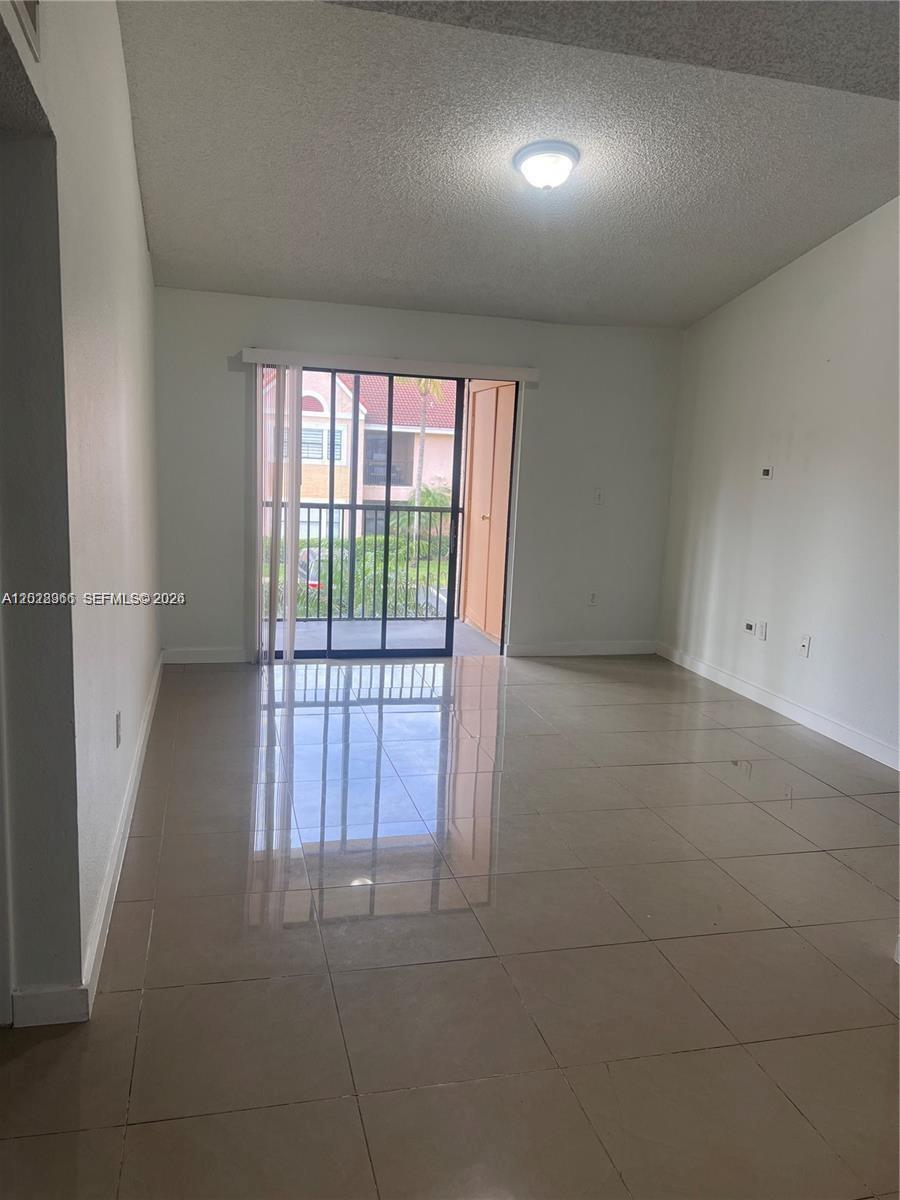 An empty room features light-colored tile flooring, white walls, and a sliding glass door — 10441 SW 156th Ct # 425, Miami FL 33196, MIAMI, FL