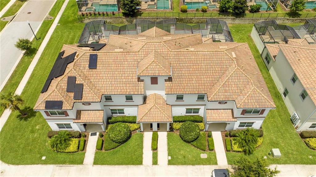 An aerial view shows a two-story duplex with a tiled roof and solar panels — 1568 PLUNKER DRIVE, DAVENPORT, FL