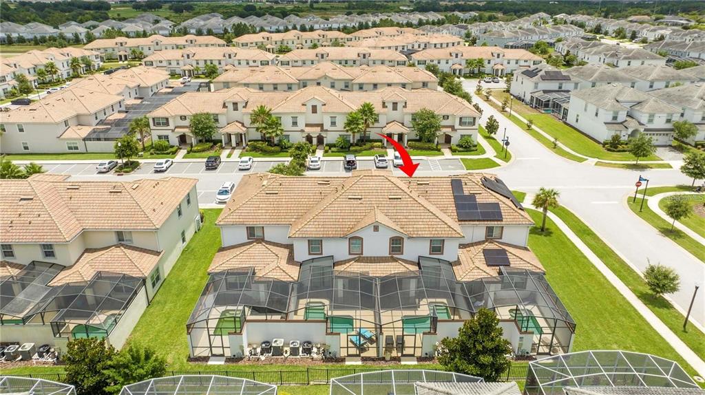 An aerial view shows a multi-unit residential building with tiled roofs and screened-in back patios — 1568 PLUNKER DRIVE, DAVENPORT, FL