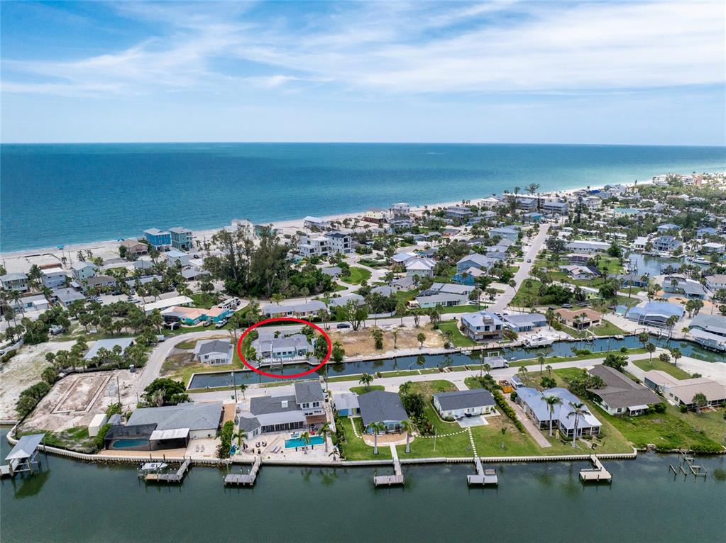 An aerial view shows a waterfront house with a pool, circled in red, near the ocean — 1265 HOLIDAY DRIVE, ENGLEWOOD, FL