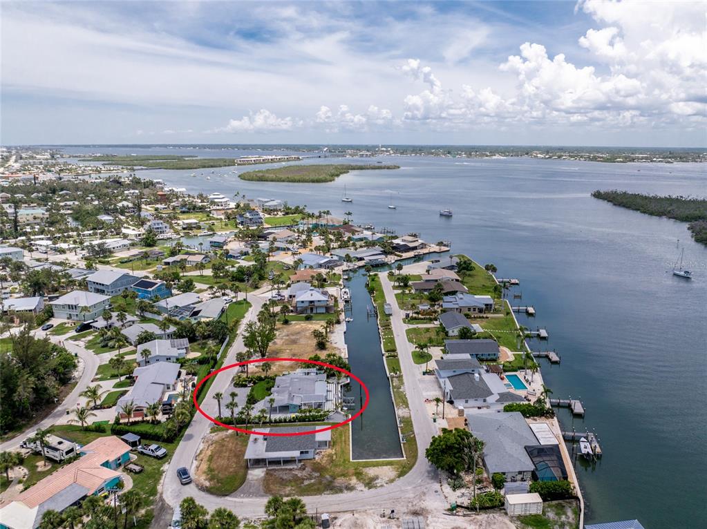An aerial view shows a waterfront house with a red circle highlighting the property — 1265 HOLIDAY DRIVE, ENGLEWOOD, FL