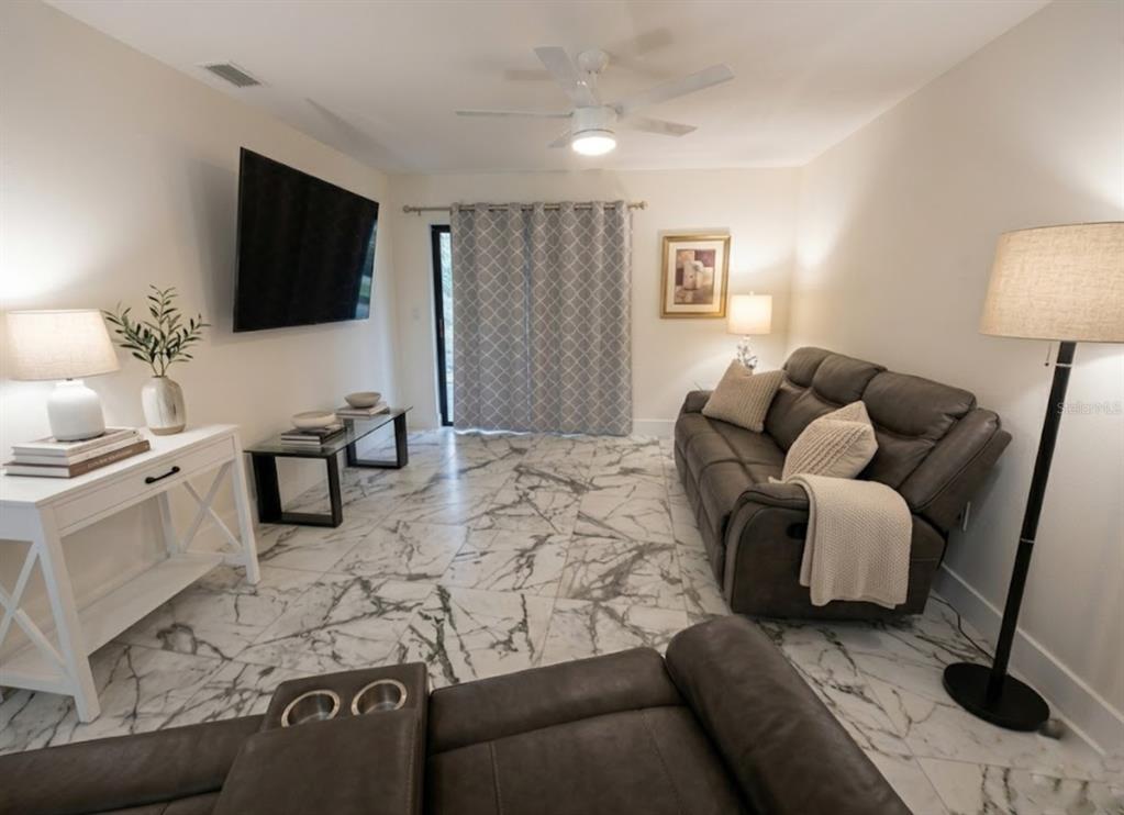 A living room features gray leather sofas, a white console table, and white marble flooring — 130 BOUNDARY BOULEVARD UNIT A&B, ROTONDA WEST, FL