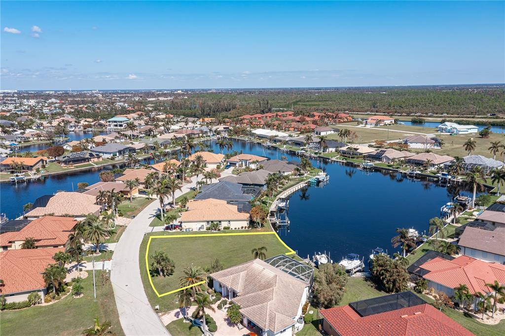 An aerial view shows a vacant waterfront lot outlined in yellow near a residential street — 3628 LICATA COURT, PUNTA GORDA, FL