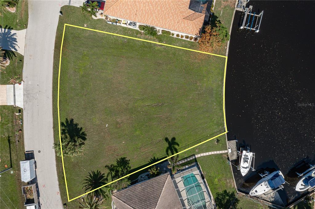 An aerial view shows a vacant, trapezoidal waterfront lot outlined in yellow — 3628 LICATA COURT, PUNTA GORDA, FL