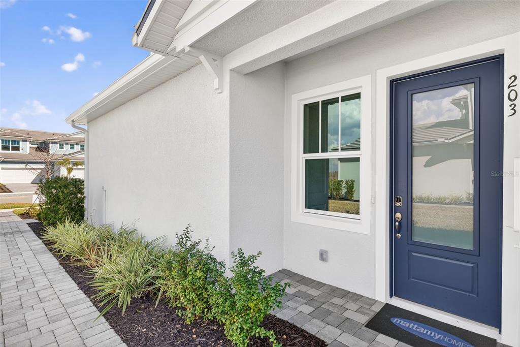 The exterior view shows a white house with a blue front door and a walkway — 17375 MOONFLOWER DRIVE UNIT 203, VENICE, FL