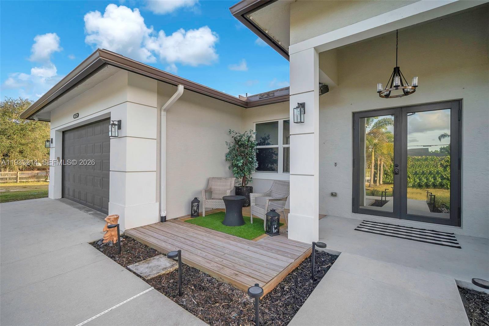 A house exterior features a garage, a small wooden deck with seating, and a glass door — 17844 N 38th Rd N, Loxahatchee FL 33470, LOXAHATCHEE, FL