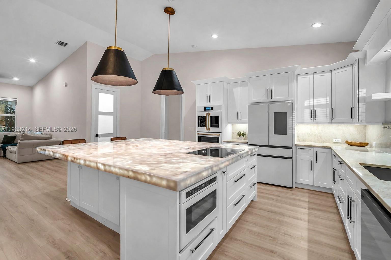 A modern kitchen features a large, illuminated stone island, white cabinetry, and stainless steel appliances — 17844 N 38th Rd N, Loxahatchee FL 33470, LOXAHATCHEE, FL