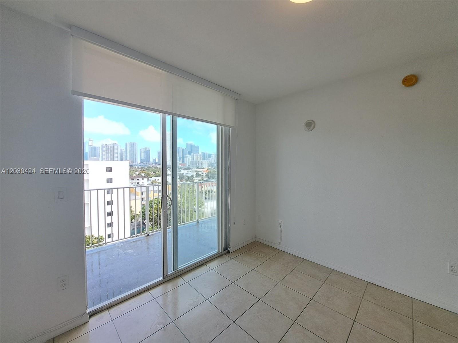 An empty room with tile flooring, white walls, and a sliding glass door to a balcony — 120 SW 8th Ave # 903, Miami FL 33130, MIAMI, FL