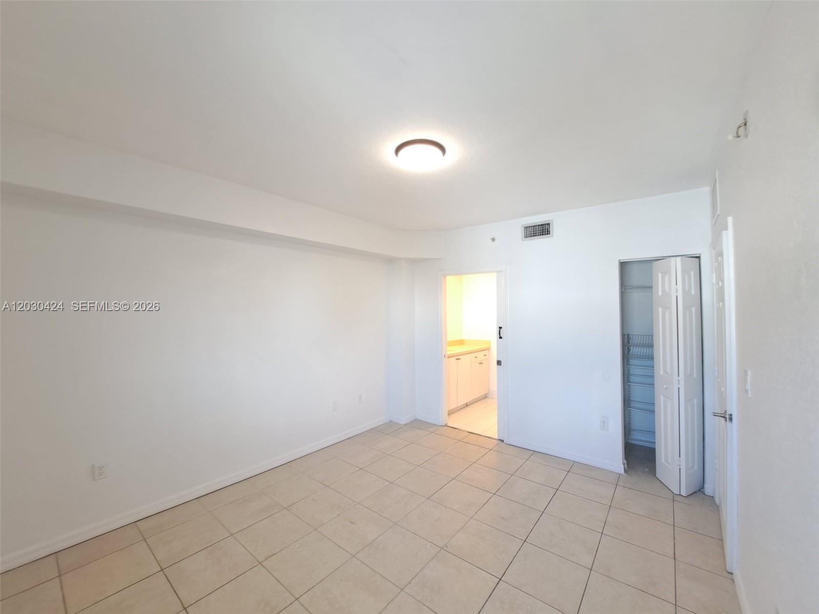 An empty room features white walls, tile flooring, a ceiling light, a closet, and a doorway — 120 SW 8th Ave # 903, Miami FL 33130, MIAMI, FL