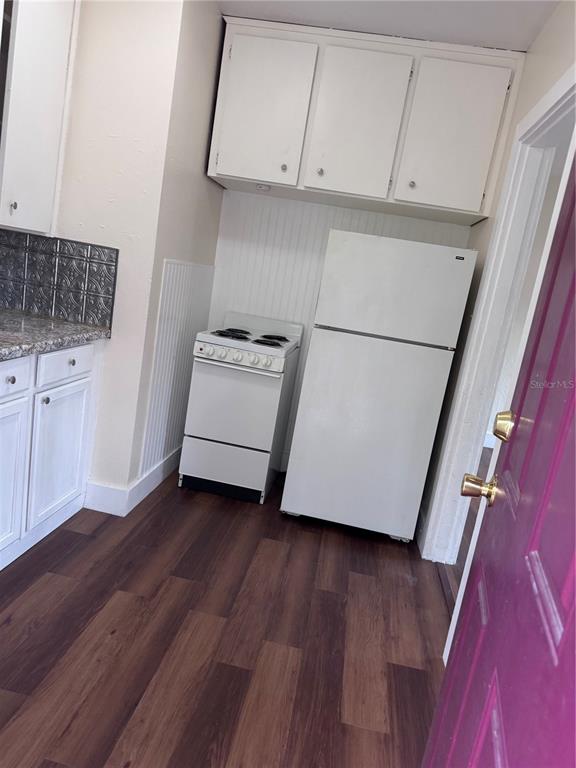 A kitchen features white cabinets, a small stove, a refrigerator, and wood-look flooring — 108 E BROADWAY STREET, FORT MEADE, FL