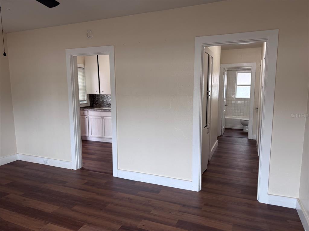 A room with wood-look flooring features two doorways leading to a kitchen and a bathroom — 108 E BROADWAY STREET, FORT MEADE, FL