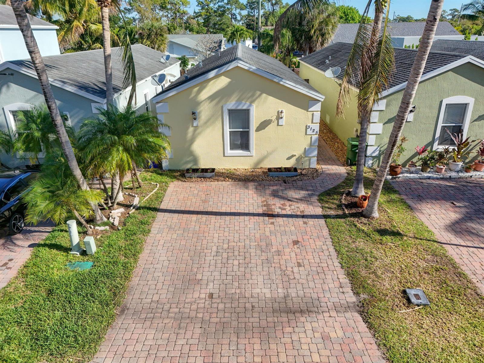 An aerial view shows a yellow house with a brick driveway and palm trees — 3125 Shelby Way Way, Palm Springs FL 33461, PALM SPRINGS, FL
