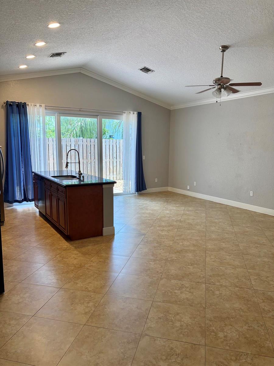 A kitchen island with a sink sits in an open-concept room with tile flooring — 3125 Shelby Way Way, Palm Springs FL 33461, PALM SPRINGS, FL