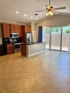 A kitchen with wood cabinets, stainless steel appliances, and tile flooring opens to a patio — 3125 Shelby Way Way, Palm Springs FL 33461, PALM SPRINGS, FL