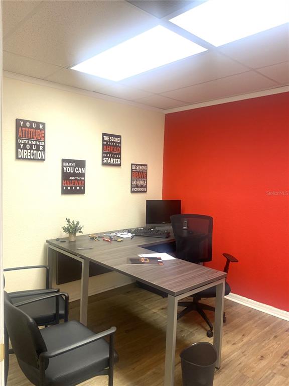 A home office features a wood-grain desk, black chairs, and a red accent wall — 7448 S US HIGHWAY 1, PORT ST LUCIE, FL