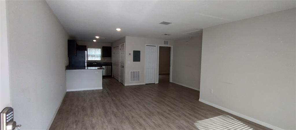 An open-concept living area features light wood-look flooring, a kitchen with dark cabinets, and white walls — 9514 N CAMEL DRIVE, CITRUS SPRINGS, FL