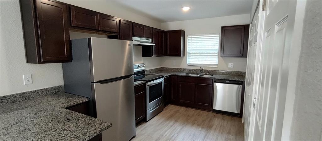 A kitchen features dark wood cabinets, granite countertops, and stainless steel appliances — 9514 N CAMEL DRIVE, CITRUS SPRINGS, FL