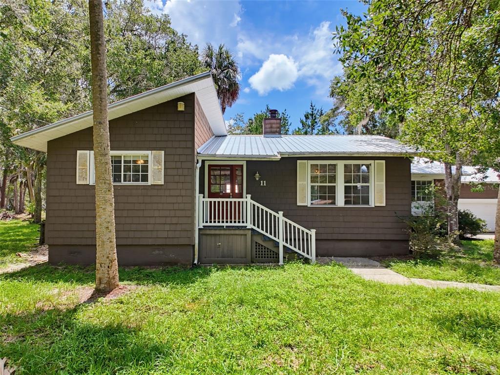 A brown house with a metal roof and white shutters sits in a wooded yard — 11 PATRICIA ROAD, YANKEETOWN, FL