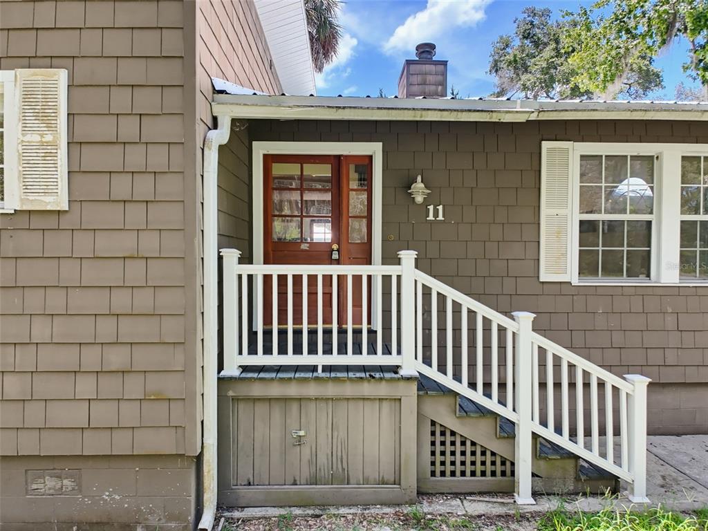 The exterior of a house features brown shingle siding, a white porch railing, and stairs — 11 PATRICIA ROAD, YANKEETOWN, FL