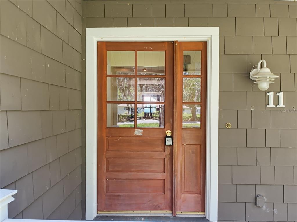 A wooden front door with glass panels and a side light sits on a porch — 11 PATRICIA ROAD, YANKEETOWN, FL
