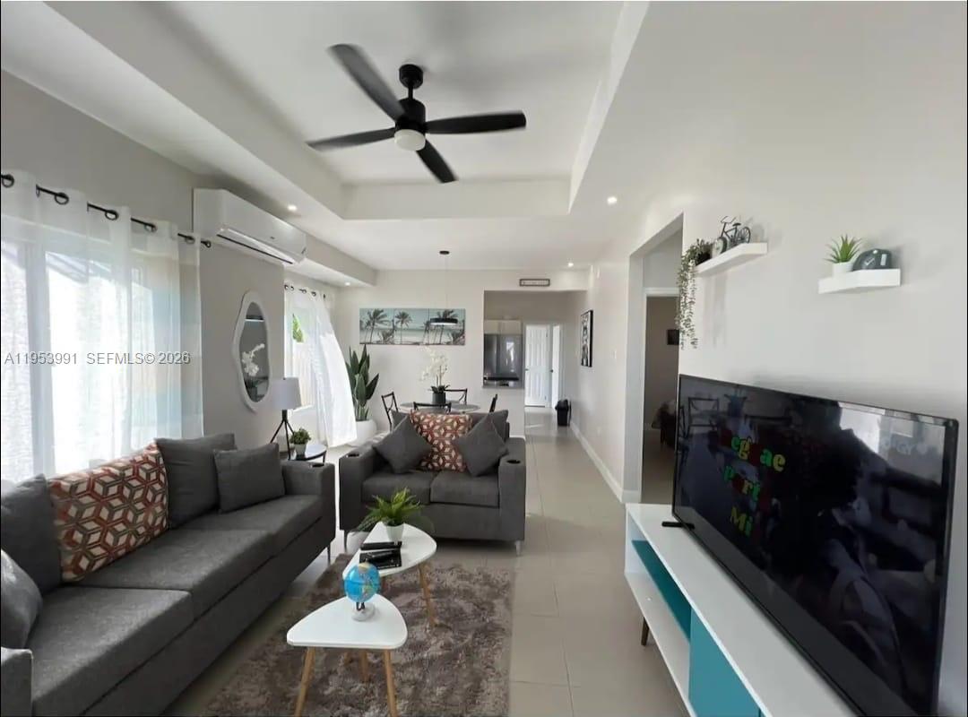 A living room features gray sofas, a television, a ceiling fan, and tile flooring — 00 Lucea, Hanover, Jamaica, FL, FL