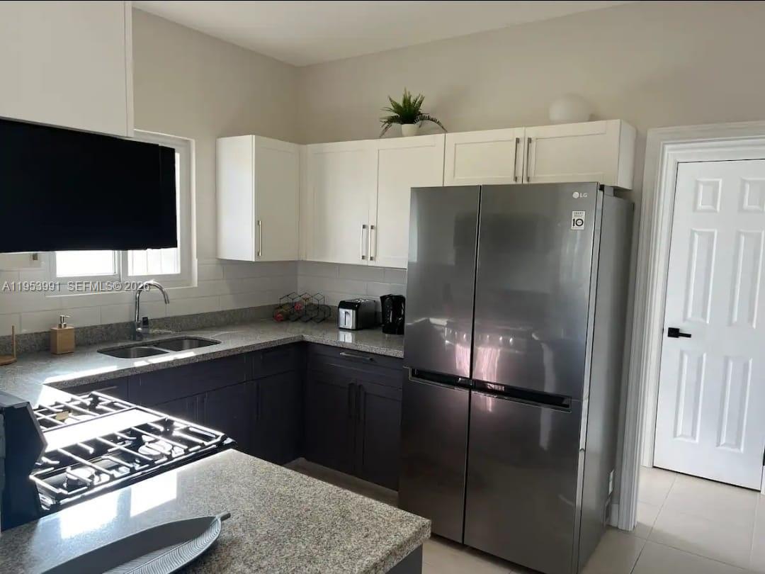 A kitchen features dark lower cabinets, white upper cabinets, granite countertops, and stainless steel appliances — 00 Lucea, Hanover, Jamaica, FL, FL