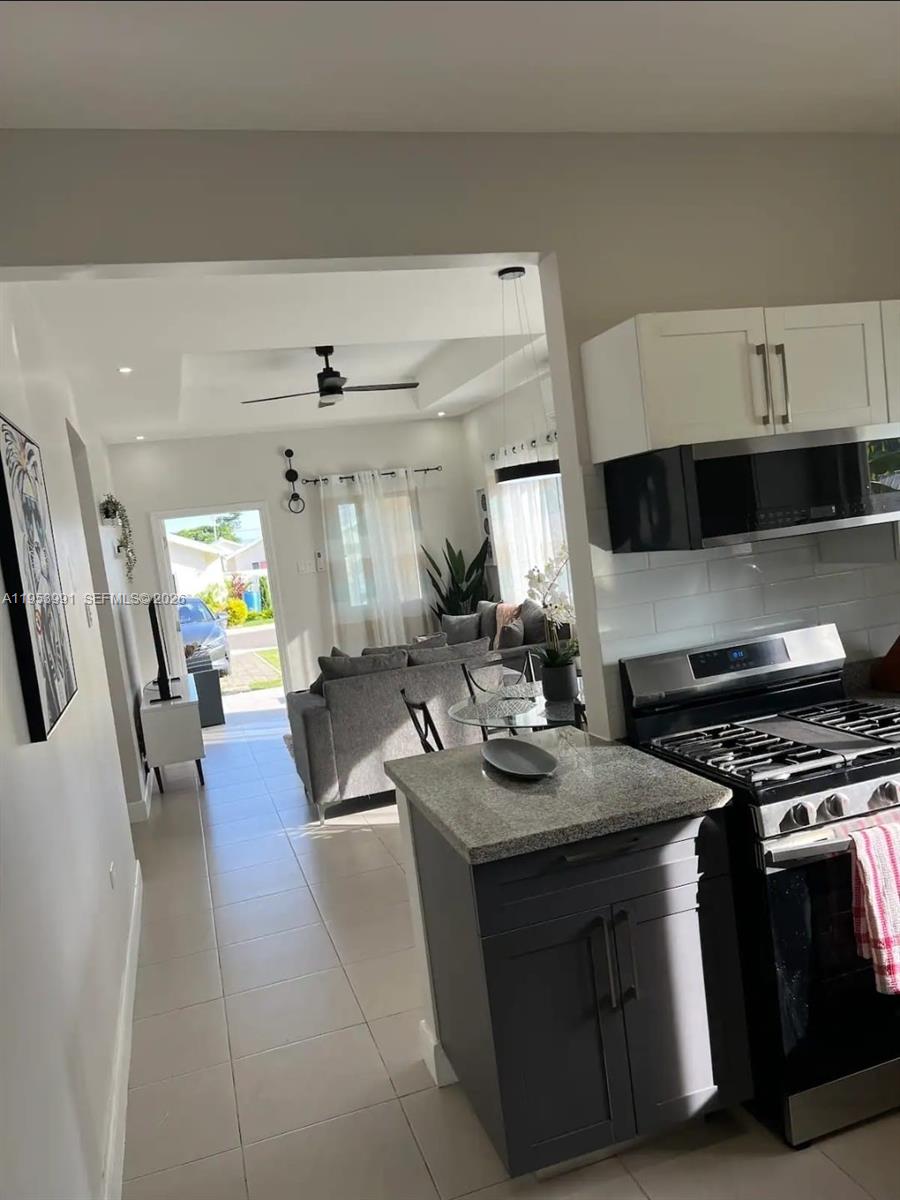 A kitchen with dark cabinets and granite countertops overlooks a living room with tile floors — 00 Lucea, Hanover, Jamaica, FL, FL