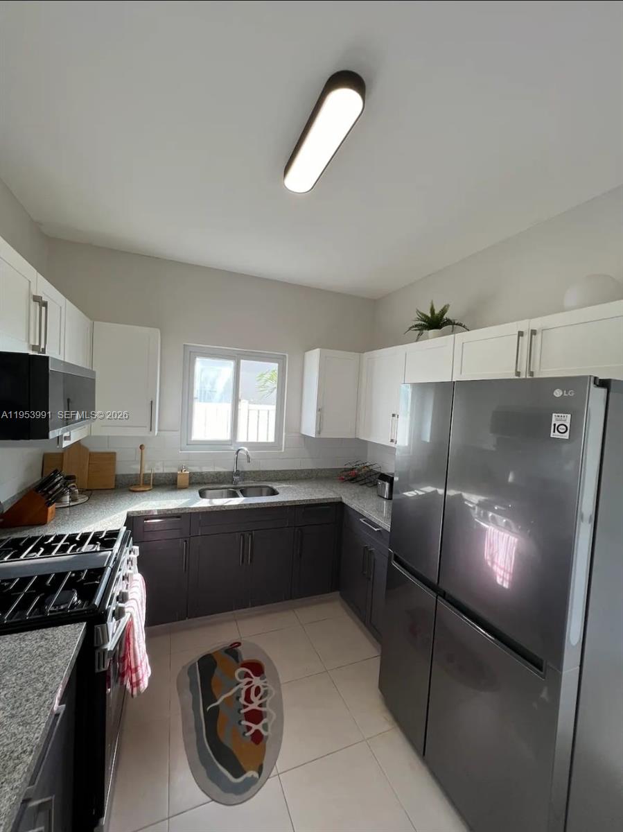 A kitchen features dark lower cabinets, white upper cabinets, stainless steel appliances, and tile flooring — 00 Lucea, Hanover, Jamaica, FL, FL