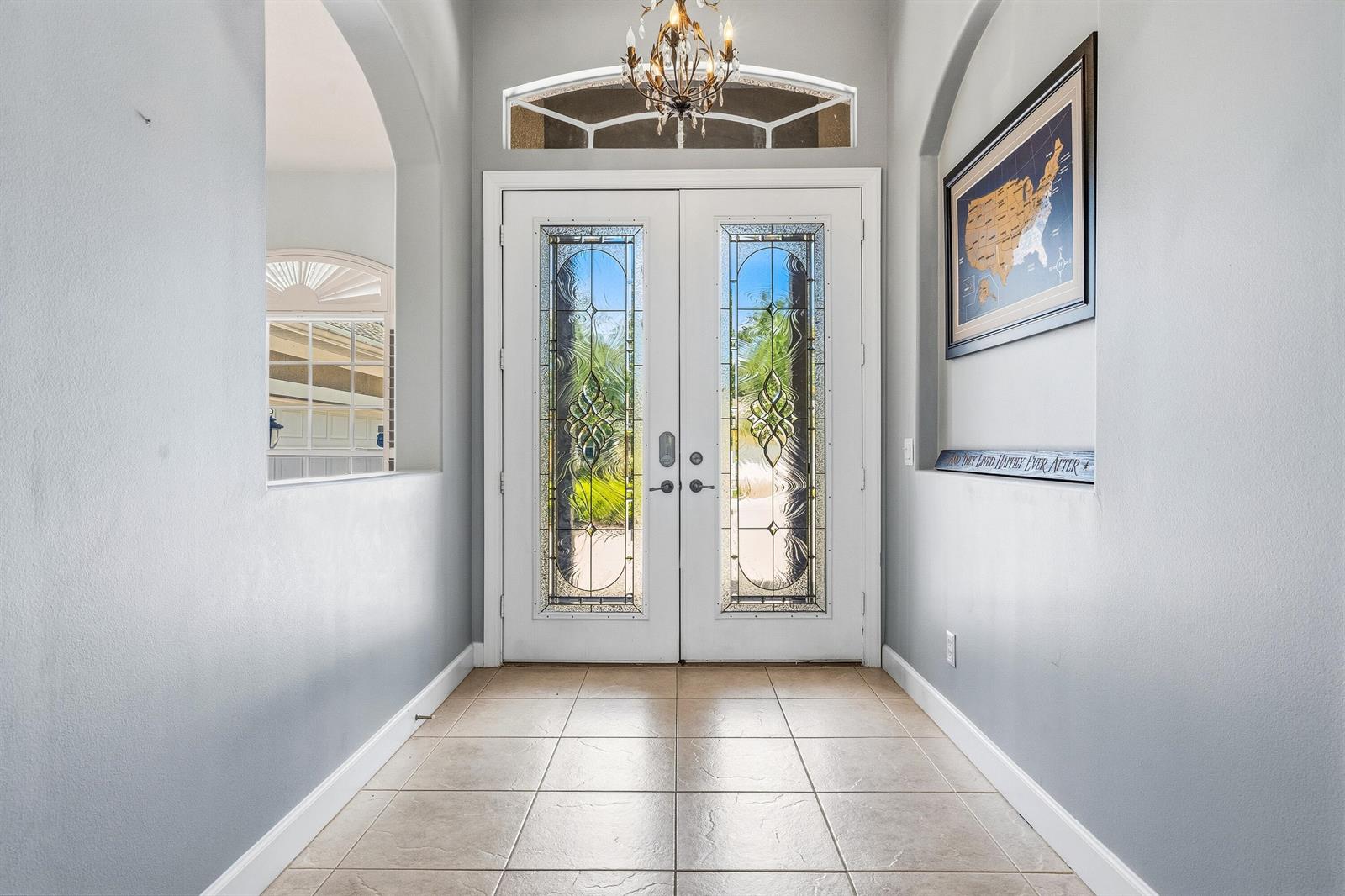 An entryway features a double front door with decorative glass, tile flooring, and a chandelier — VERO BEACH, FL