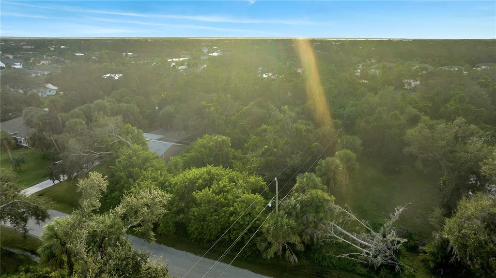 An aerial view shows a wooded residential lot with a house partially obscured by trees — 4355 MELIS STREET, PORT CHARLOTTE, FL