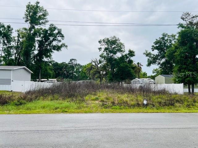 A vacant, overgrown lot sits between two houses behind a white vinyl fence — Lot 4 NW 13th ST, OCALA, FL