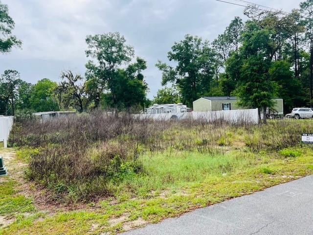 A vacant, overgrown lot sits next to a white fence and a mobile home — Lot 4 NW 13th ST, OCALA, FL