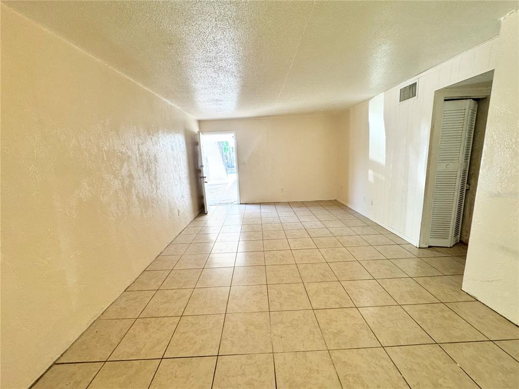An empty room with beige tile flooring, light-colored walls, and an open exterior door — 1229 KENNEDY ROAD UNIT 43, DAYTONA BEACH, FL