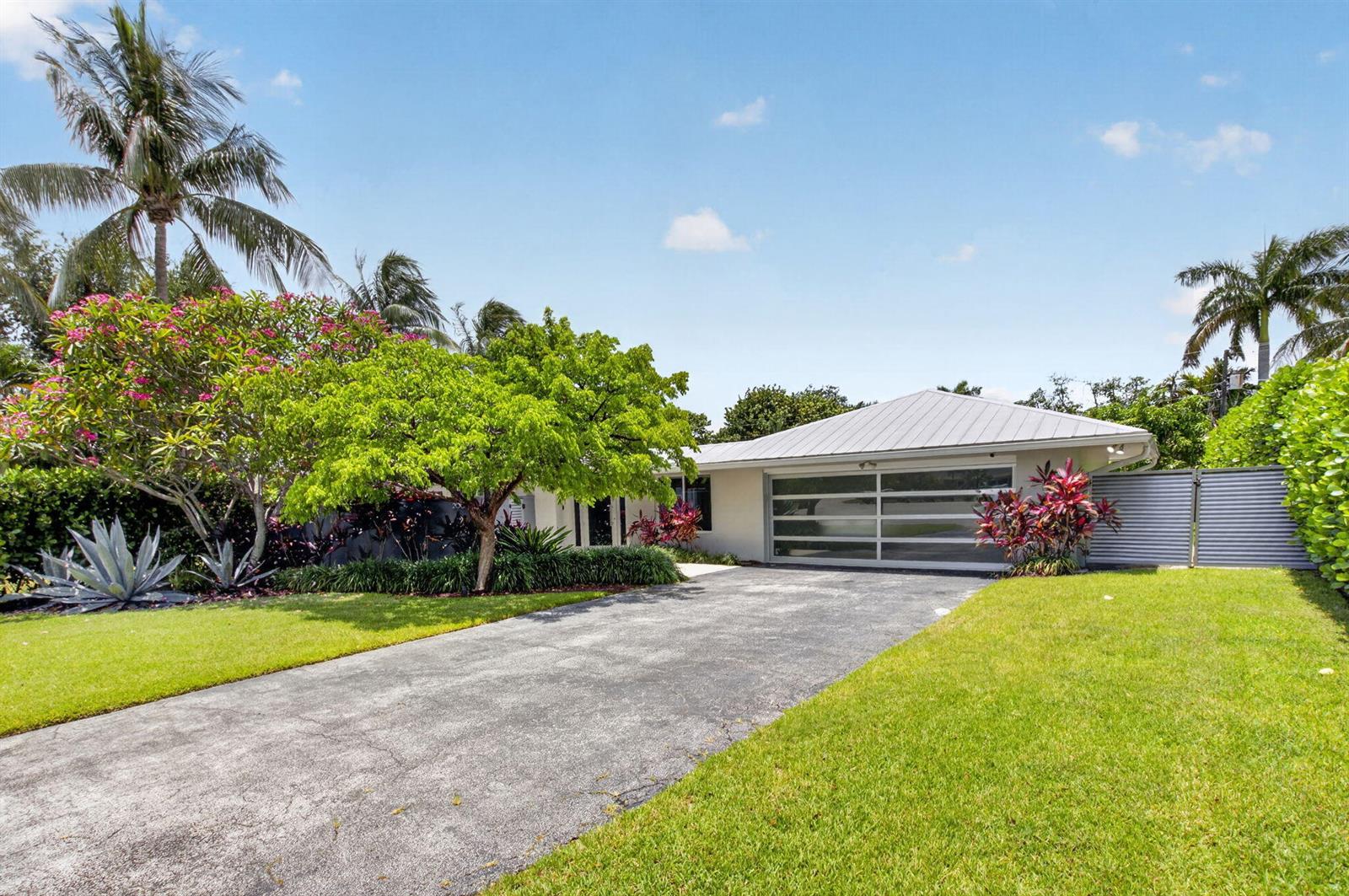 A single-story house with a metal roof, a modern glass garage door, and lush landscaping — 2006 NW 3rd Avenue, Delray Beach FL 33444, DELRAY BEACH, FL