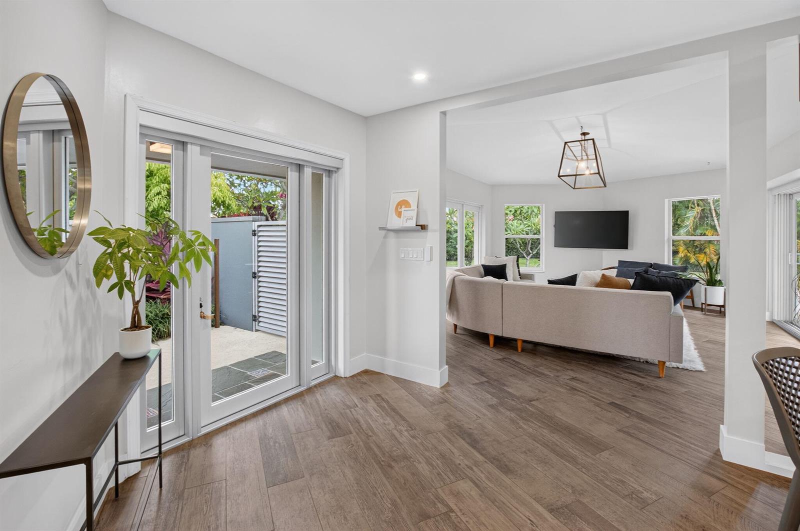 An entryway with wood-look tile floors leads into a living room with a sectional sofa — 2006 NW 3rd Avenue, Delray Beach FL 33444, DELRAY BEACH, FL