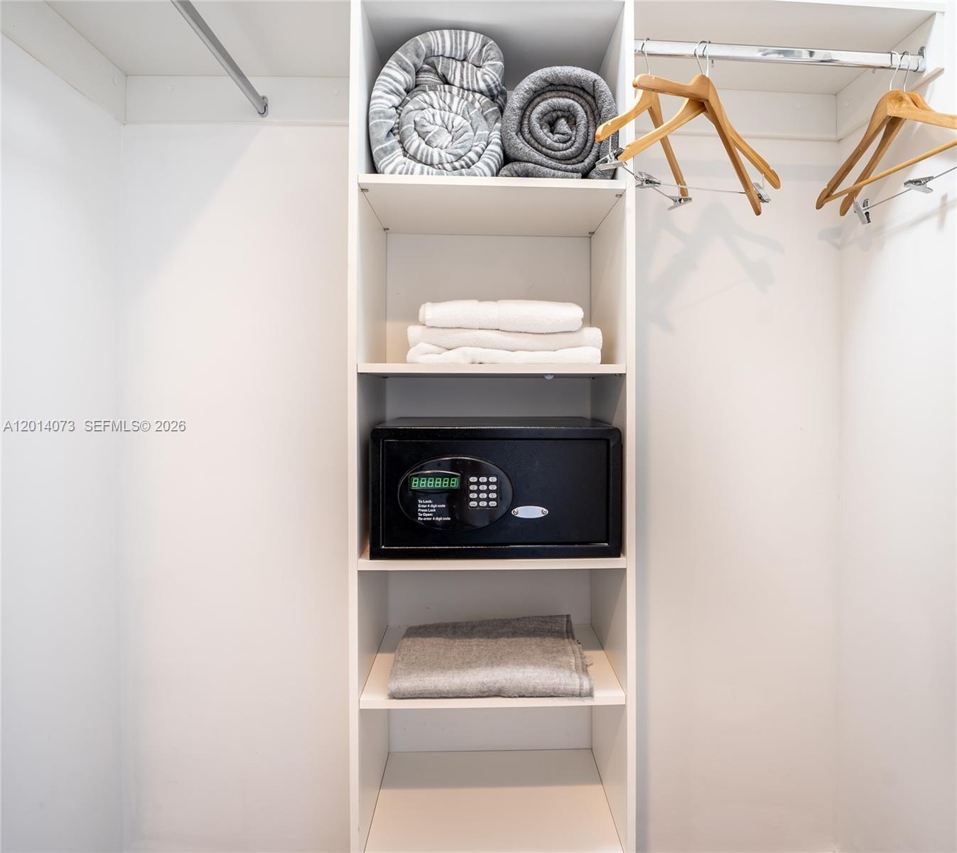 A white closet features a central shelving unit with blankets, towels, and a digital safe — 2602 E Hallandale Beach Blvd # R806, Hallandale Beach FL 33009, HALLANDALE BEACH, FL
