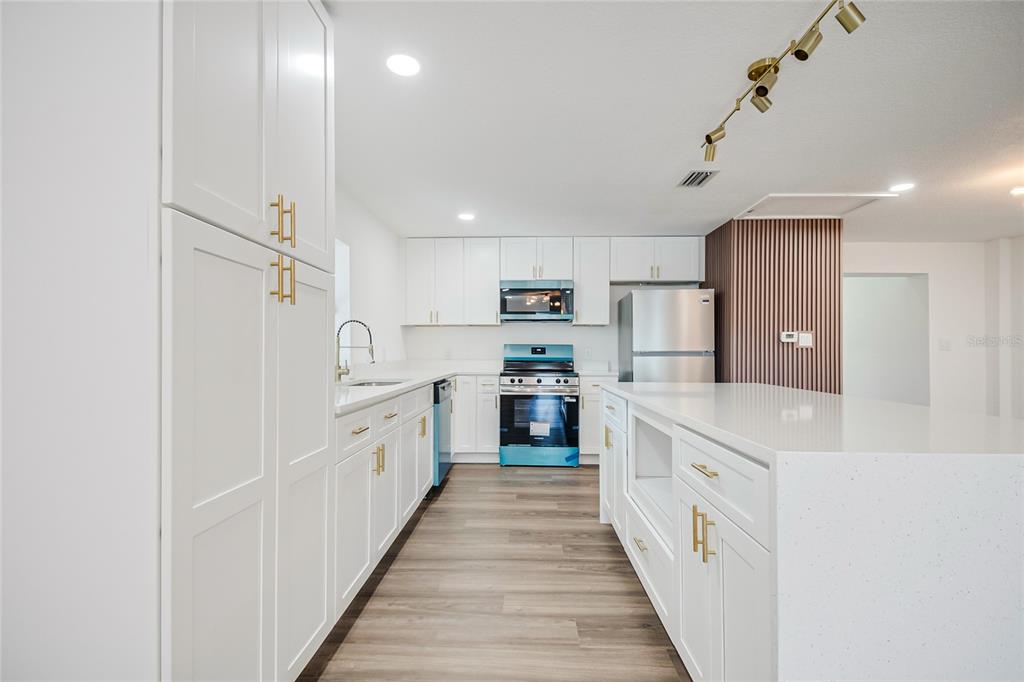 A modern kitchen features white cabinets, stainless steel appliances, a large island, and wood flooring — 842 DENNIS AVENUE, ORLANDO, FL