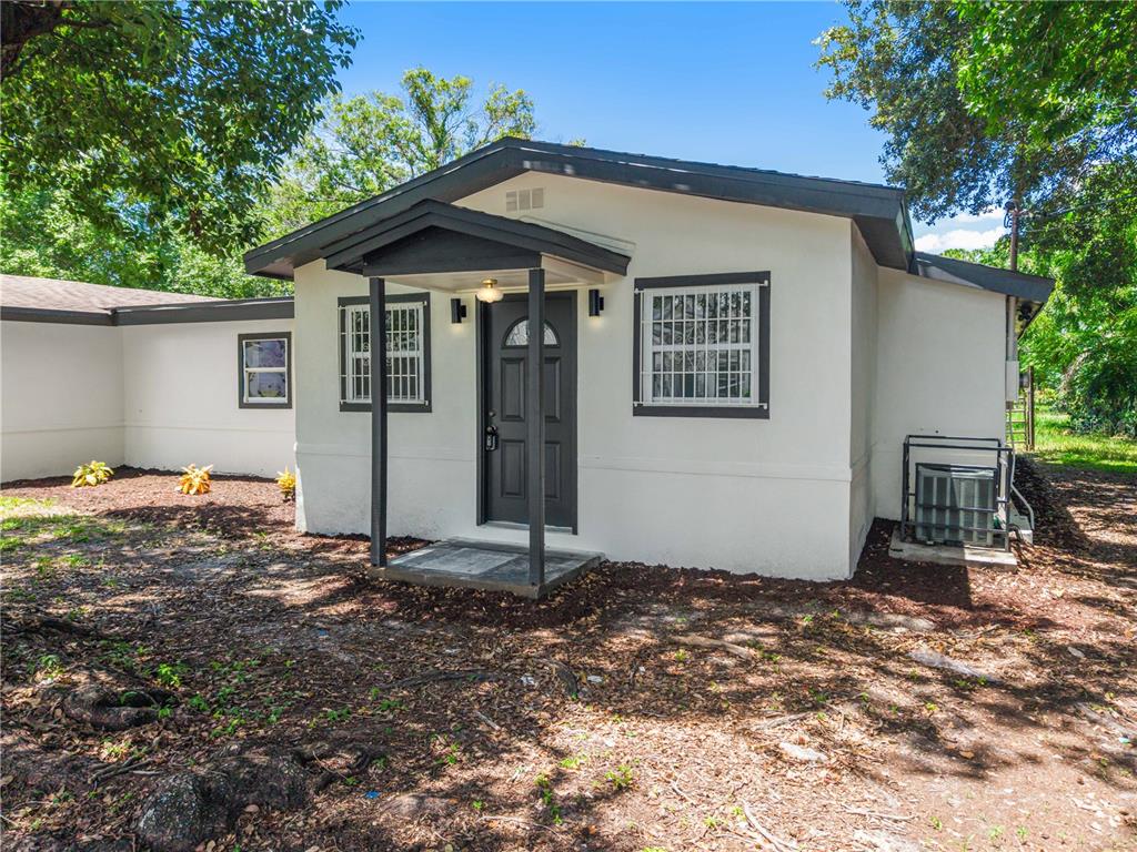 A white exterior house with a dark gray front door, porch, and window trim — 842 DENNIS AVENUE, ORLANDO, FL