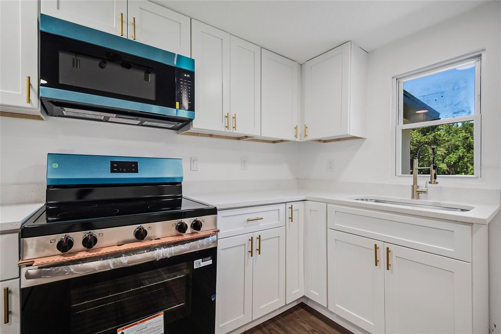 A kitchen features white cabinets, gold hardware, a new stove, and a window above the sink — 842 DENNIS AVENUE, ORLANDO, FL