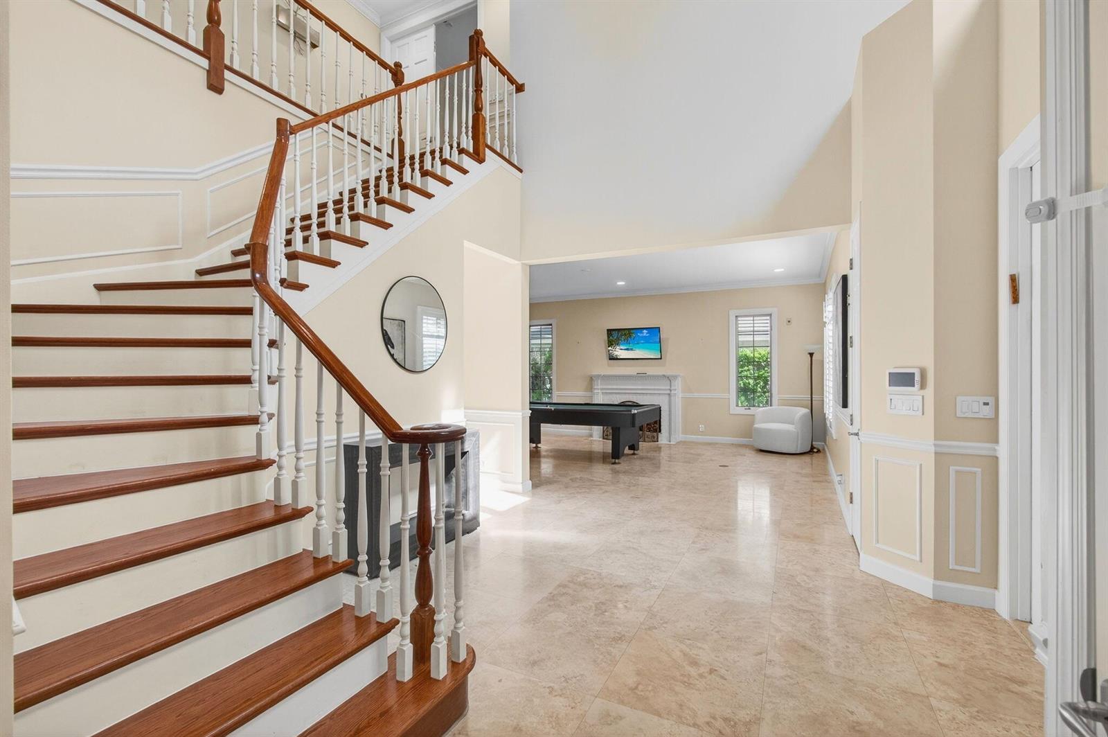 A foyer with a curved wooden staircase leads to a room featuring a pool table — 6167 NW 23rd Way, Boca Raton FL 33496, BOCA RATON, FL