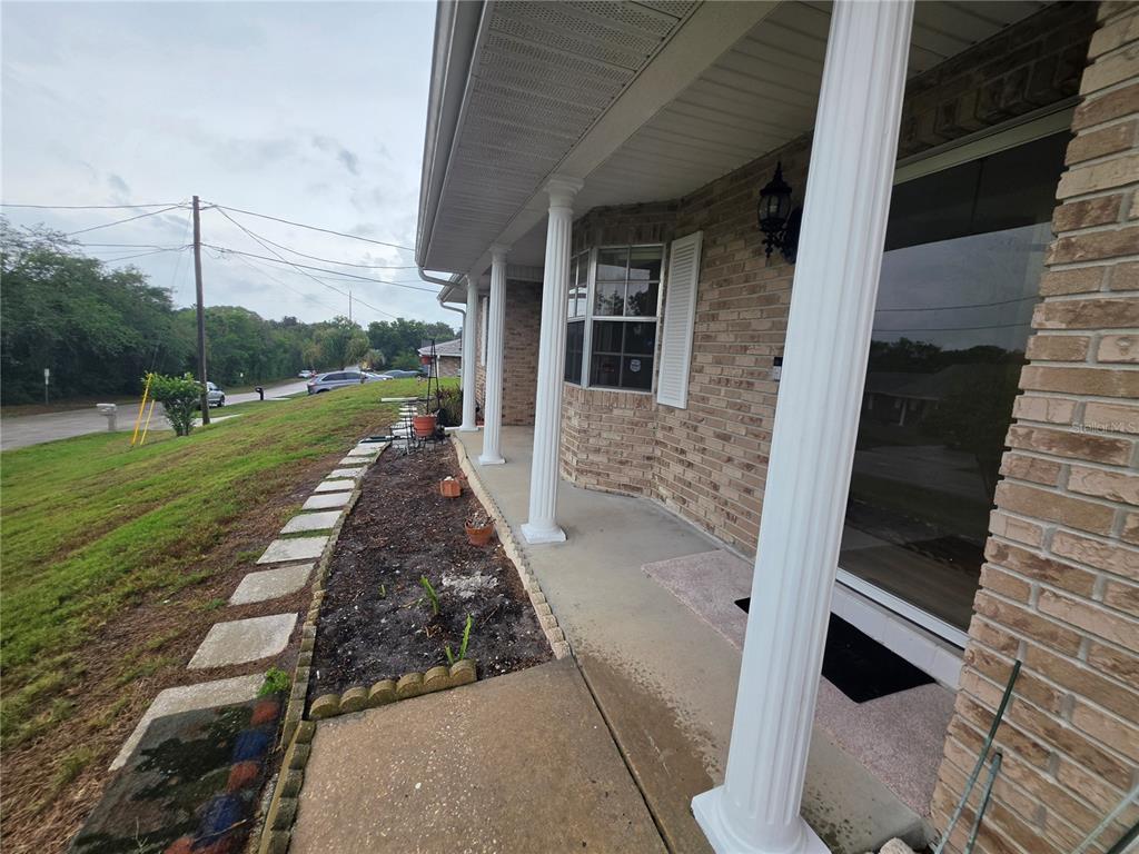 A brick house exterior features a covered front porch with white columns and a walkway — 1732 TOPAZ TERRACE, DELTONA, FL