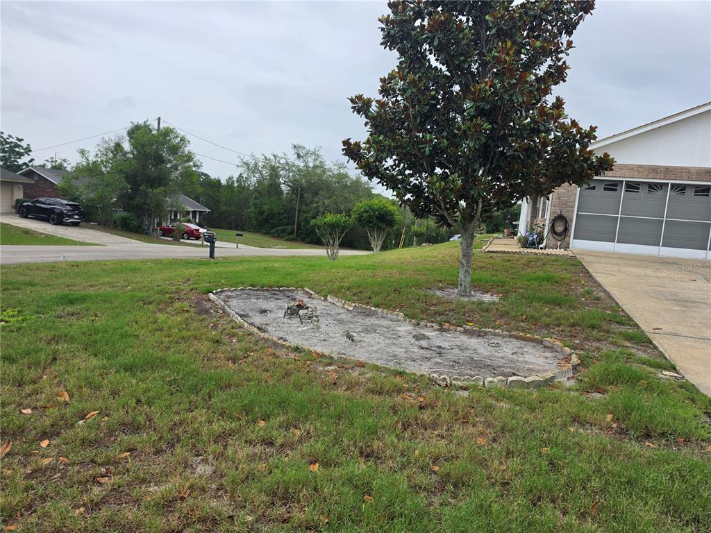 A front yard features a landscaped garden bed with stone edging near a paved driveway — 1732 TOPAZ TERRACE, DELTONA, FL