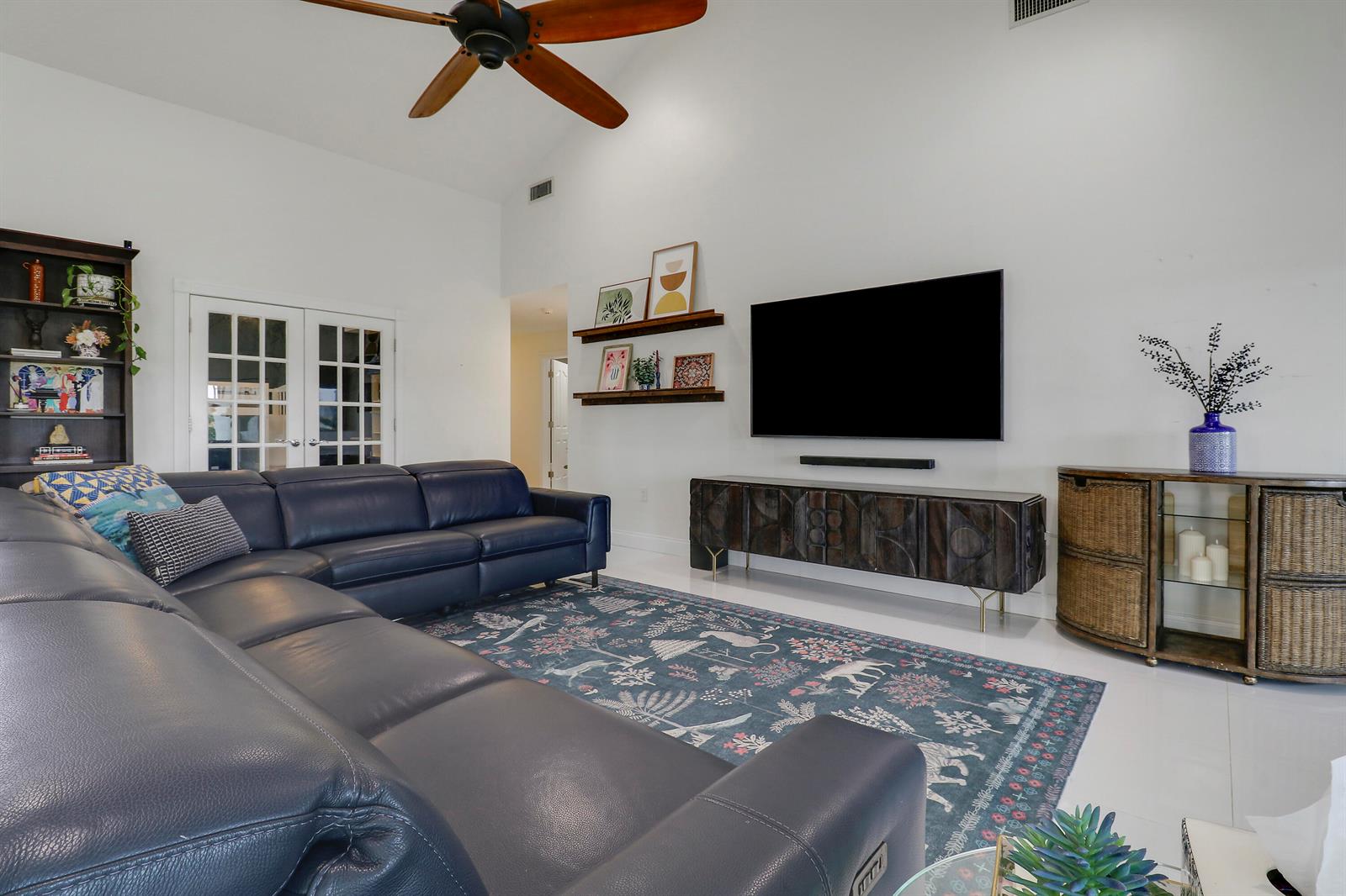 A living room features a blue leather sectional, a patterned rug, and a wall-mounted television — 1560 Wilderness Road, West Palm Beach FL 33409, WEST PALM BEACH, FL