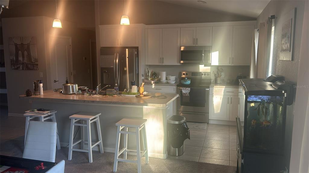 A kitchen features white cabinets, stainless steel appliances, a center island, and tile flooring — 8316 NEVADA STREET, SPRING HILL, FL