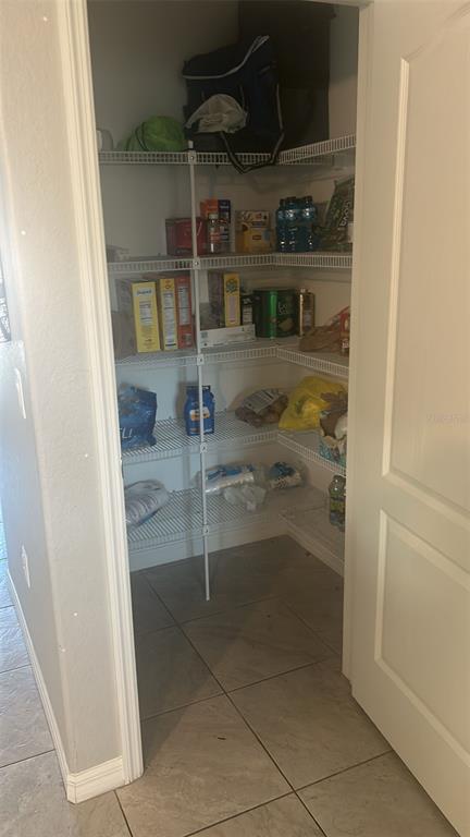 A walk-in pantry with white wire shelving, tiled flooring, and a white door — 8316 NEVADA STREET, SPRING HILL, FL