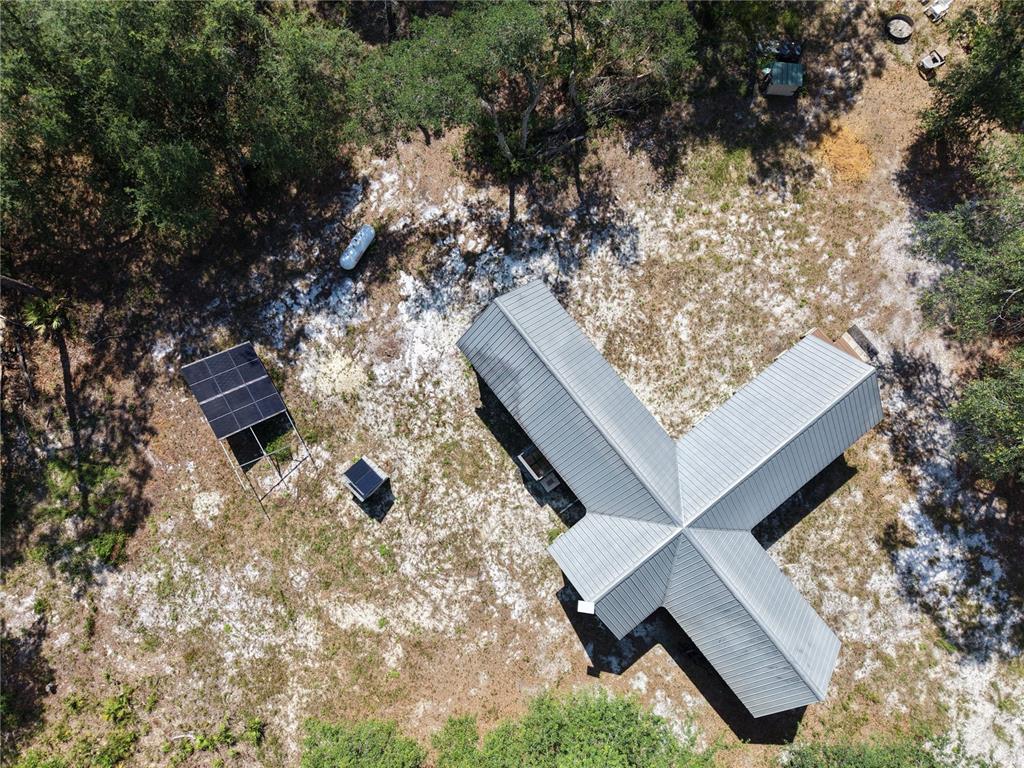 An aerial view shows a cross-shaped house with a metal roof, solar panels, and propane tank — 375 BUCK SPRINGS ROAD, PALATKA, FL