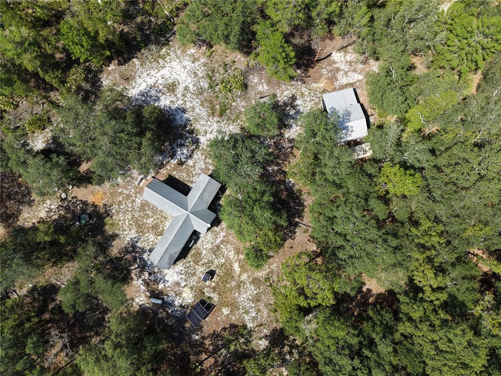 An aerial view shows two metal-roofed buildings situated in a wooded, sandy lot — 375 BUCK SPRINGS ROAD, PALATKA, FL