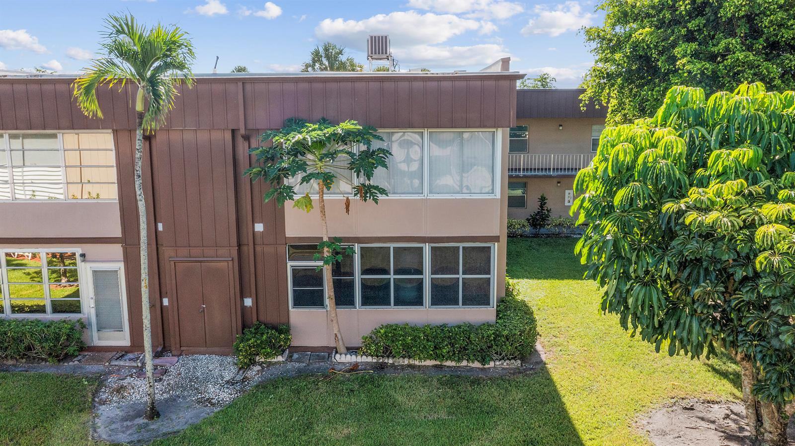 An exterior view of a two-story apartment building with brown siding and a small tree — 344 Piedmont, Delray Beach FL 33484, DELRAY BEACH, FL